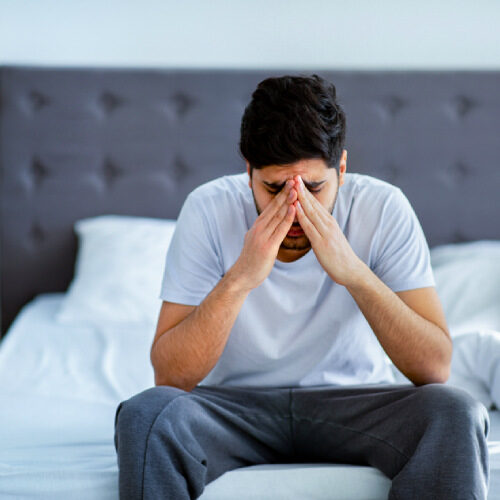 san diego naturopathic doctors man sitting edge of bed holding head in pain