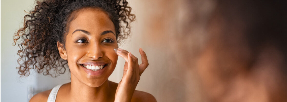 san diego naturopathic doctors woman smiling into mirror rubbing facial cream