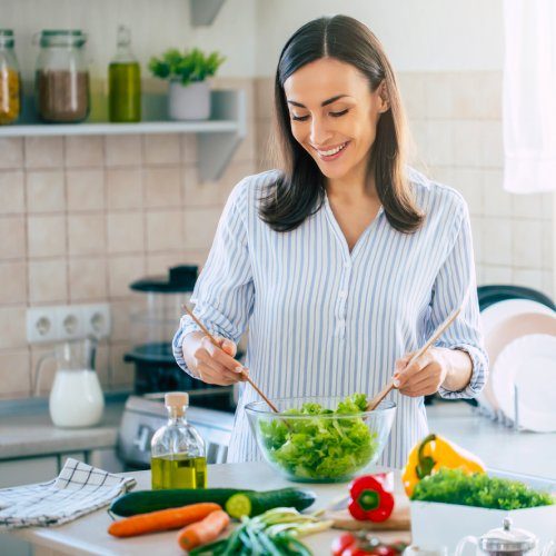 san-diego-naturopathic-doctors-smiling-woman-cutting-vegetables-on-kitchen-countertop