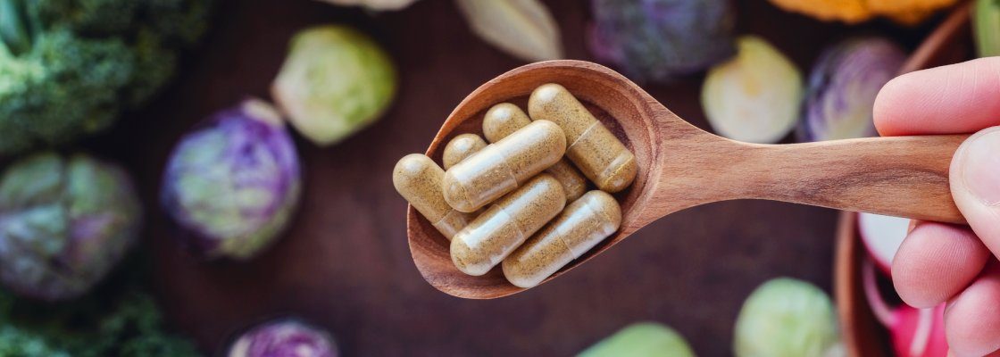 san diego naturopathic doctors spoon full of supplements beside vegetables top view