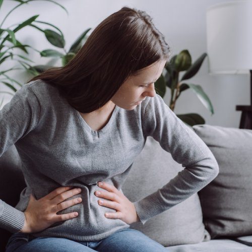 san diego naturopathic doctors woman sitting couch holding gut in pain