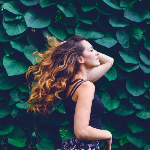 san diego naturopathic doctors woman walking smiling infront of wall of green leaves